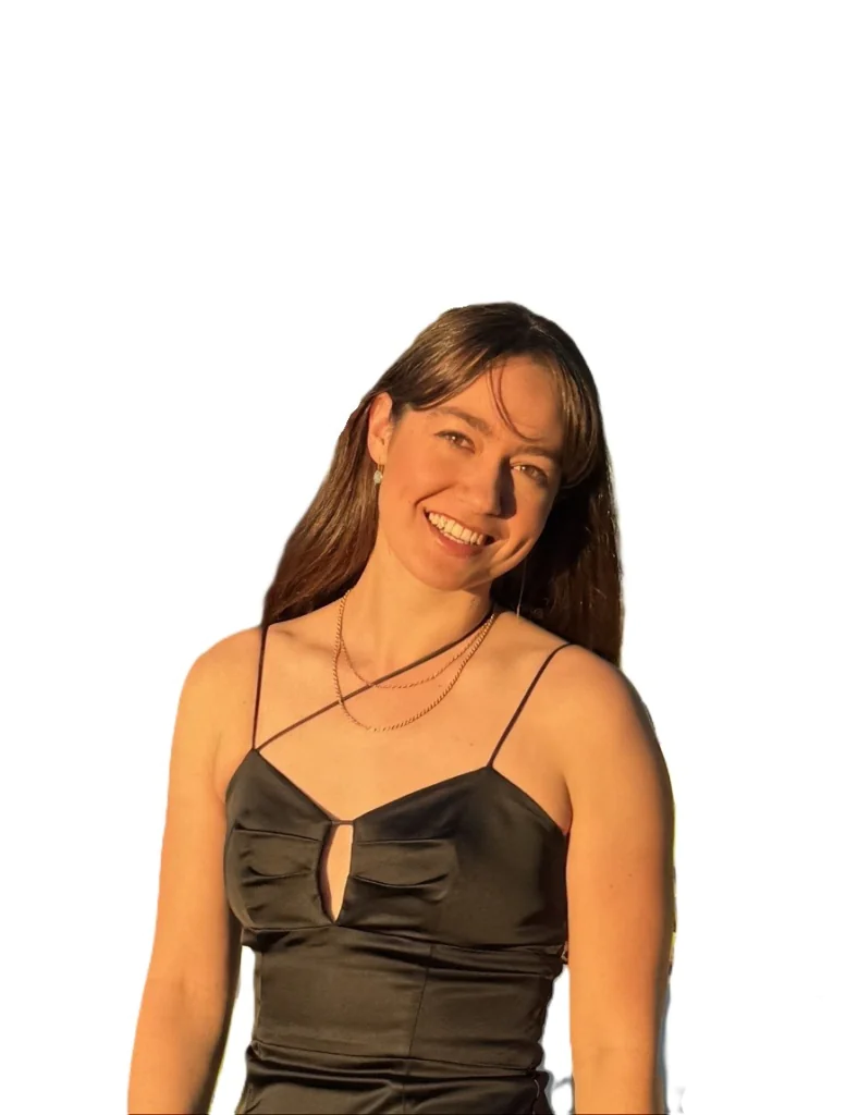 Smiling woman in a black satin spaghetti-strap dress with a small front cutout, standing against a white background.