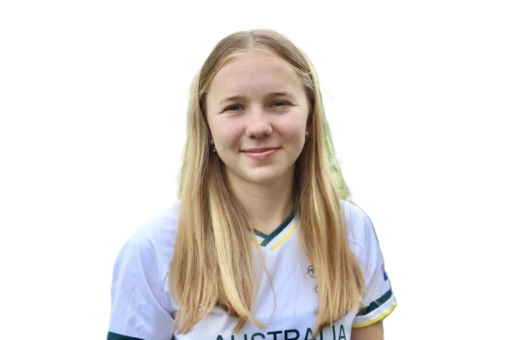 Smiling teenage girl with long blonde hair wearing a white Australia sports jersey, facing the camera.