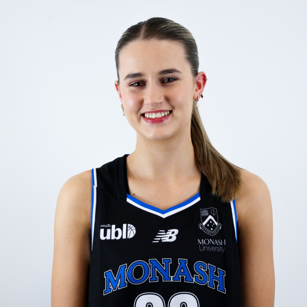 Smiling young woman in a black Monash University basketball jersey facing the camera.