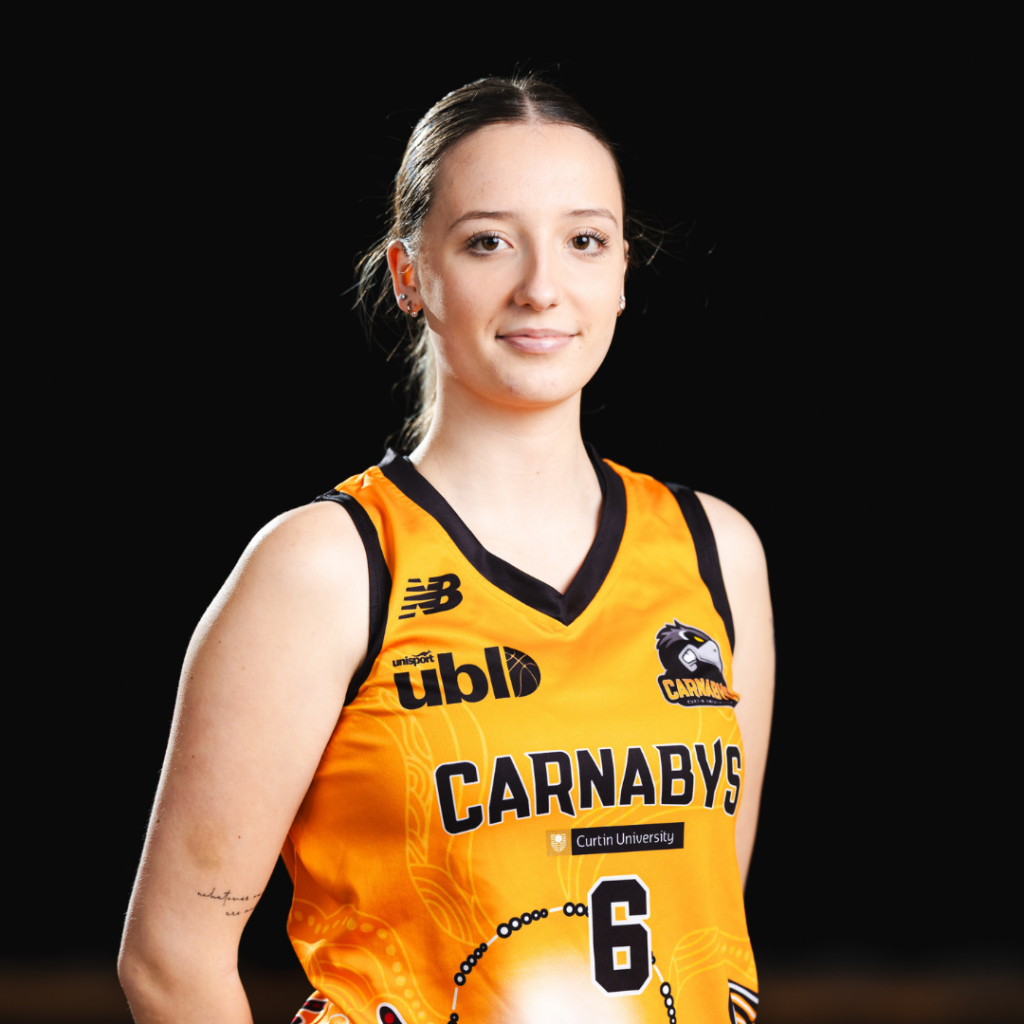 Portrait of a female basketball player in an orange Carnabys jersey with number 6, smiling against a black background.