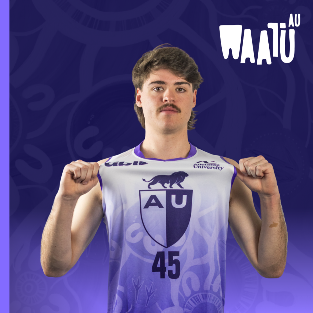 Male athlete wearing a white-to-purple AU jersey with number 45, posing with fists up against a purple background featuring AU branding.