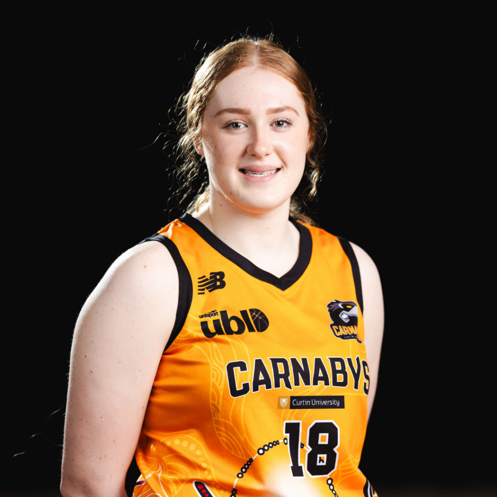 Portrait of a female athlete in an orange Carnabys jersey, number 18, posing against a dark studio backdrop with a smile.